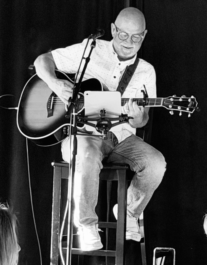 Danny Dukes seated with his acoustic guitar